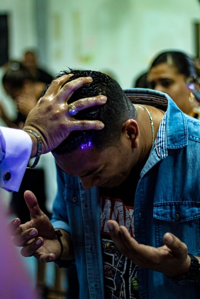 Foto de Su Casa Panamá A man deeply immersed in a religious ceremony, hands placed on his head.