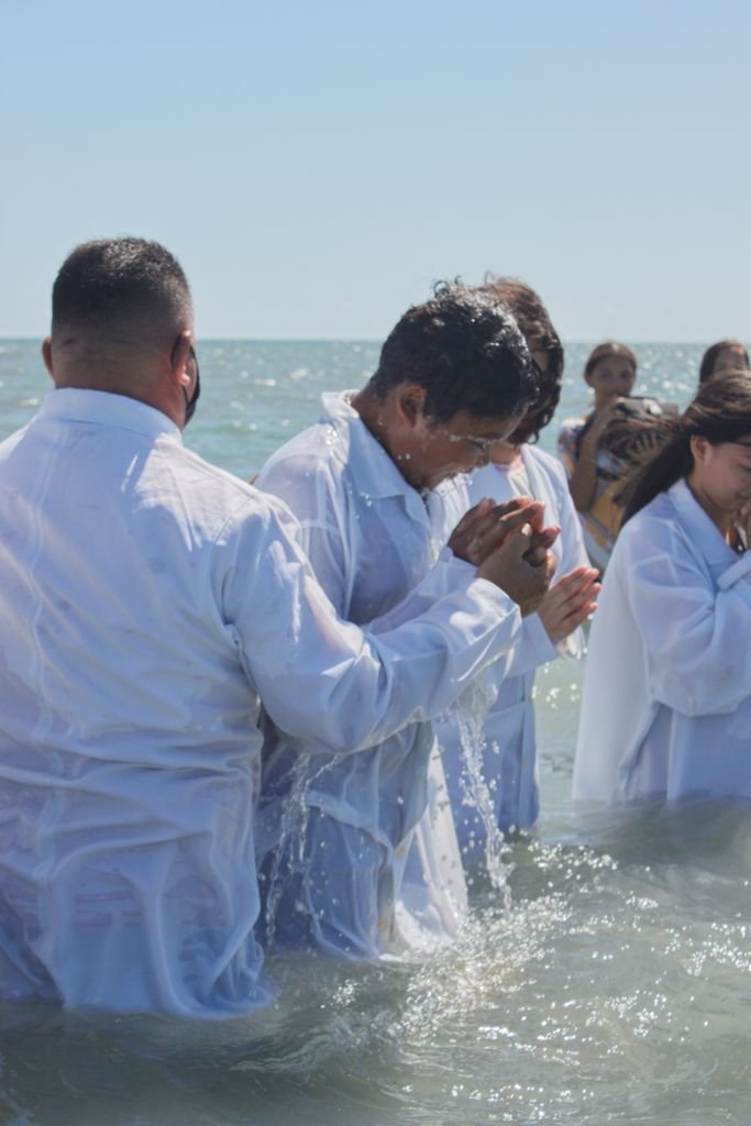 Foto de Carlos Daniel A spiritual baptism ceremony in the ocean with men and women dressed in white robes.