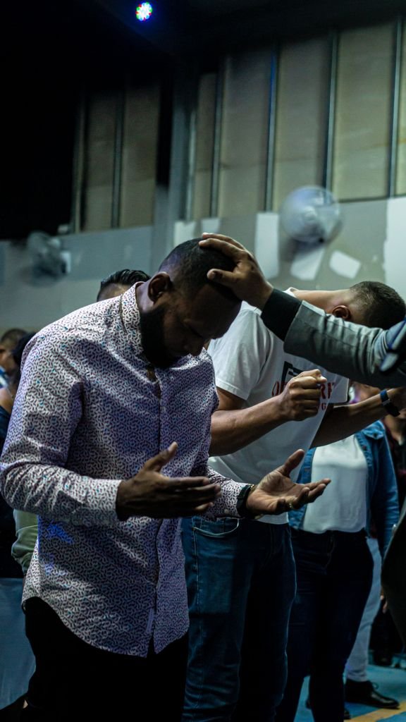 Foto de Su Casa Panamá Men engaged in a spiritual prayer gathering inside a worship venue, reflecting devotion.