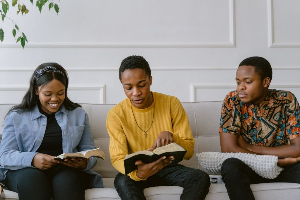 Foto de Tima Miroshnichenko Three young adults enjoying reading books together in a comfortable indoor setting.
